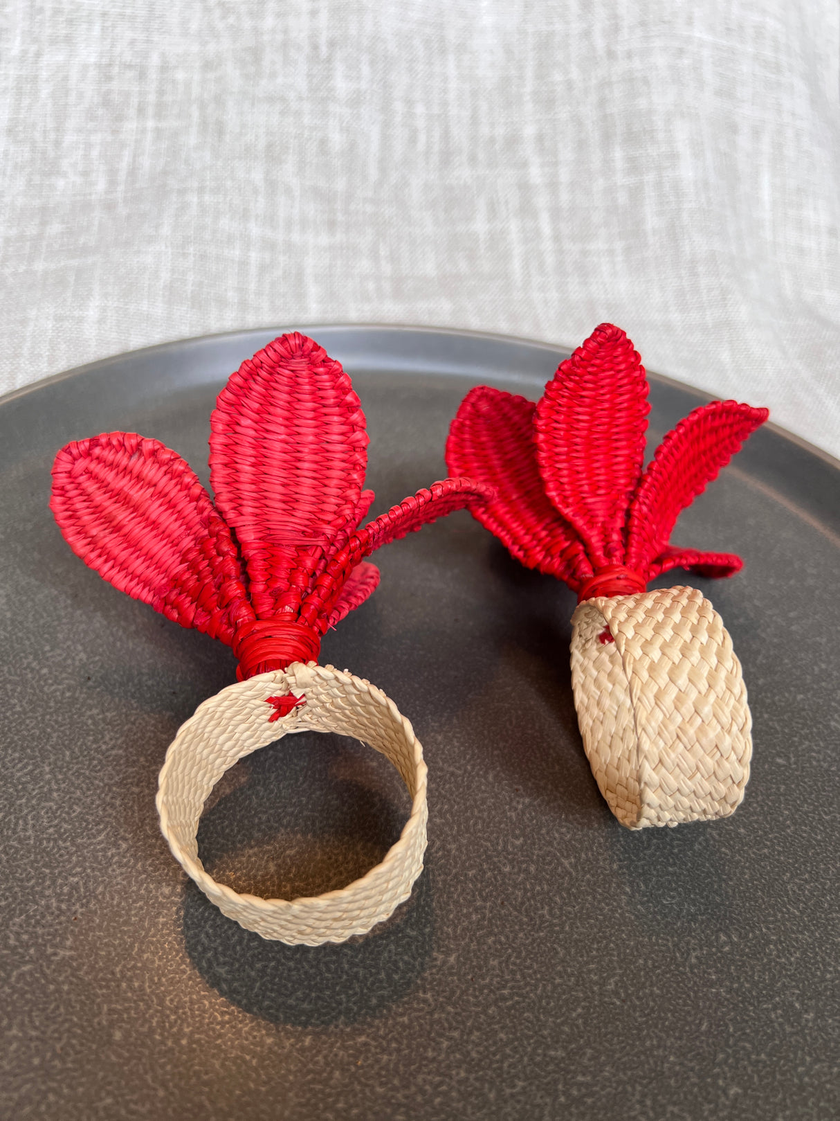 Red woven flower napkin rings on a dark surface