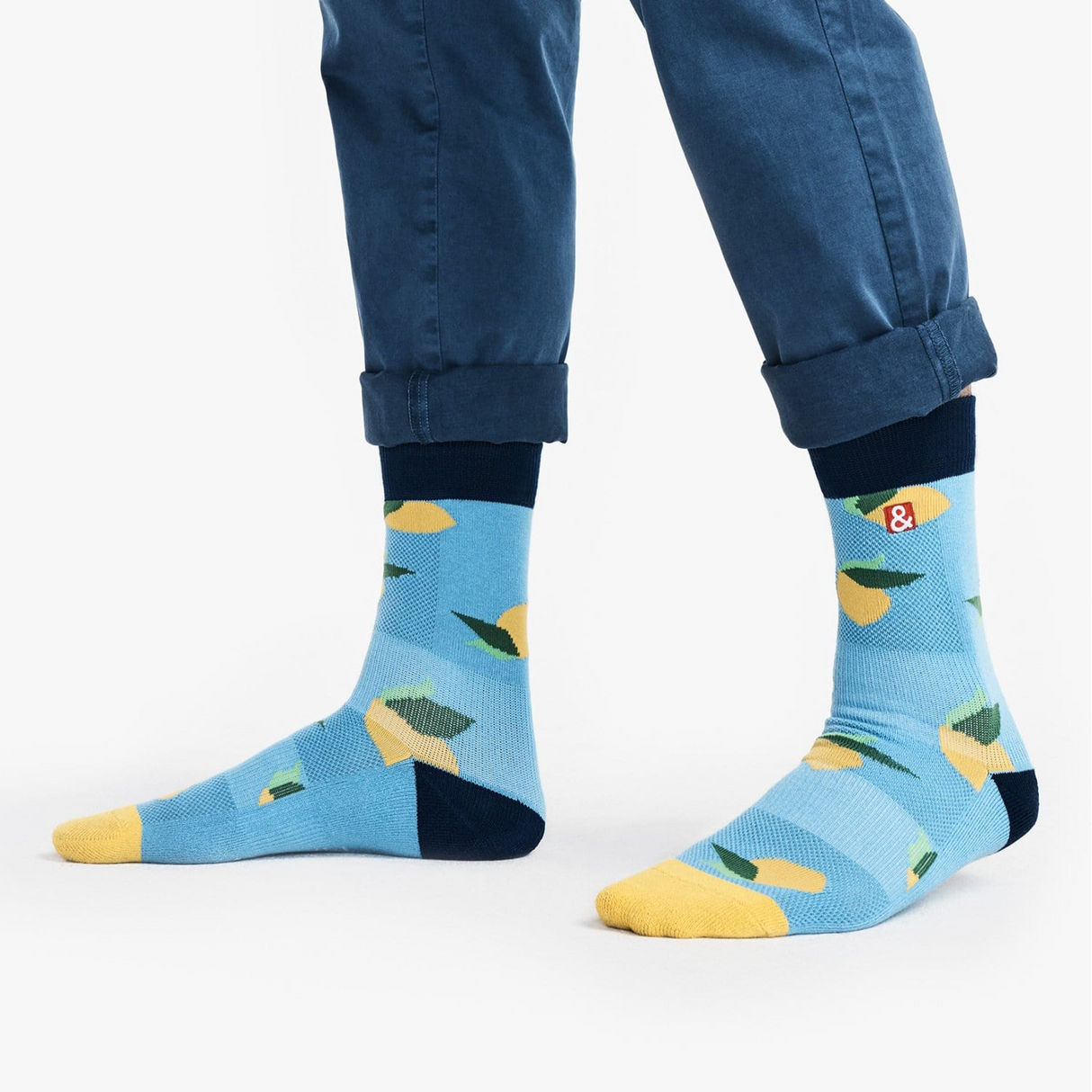 Blue socks with lemon pattern worn by a person in blue pants on a white background