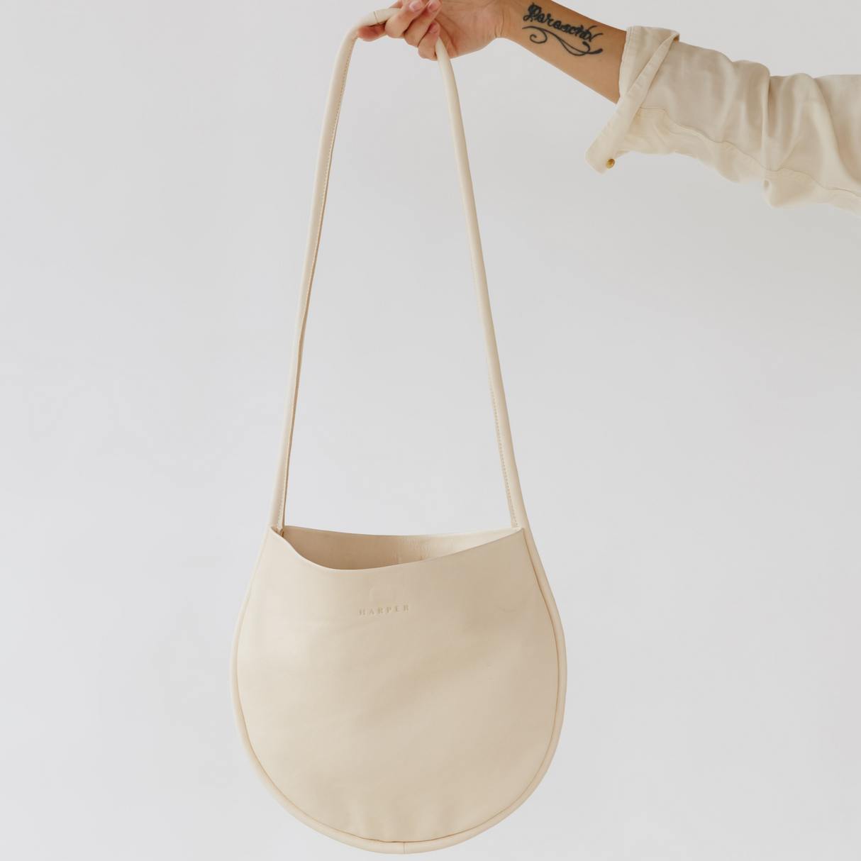 Beige handbag held by a person against a white background