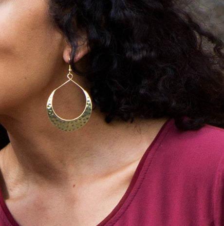 Woman wearing gold hoop earrings with a blurred natural background