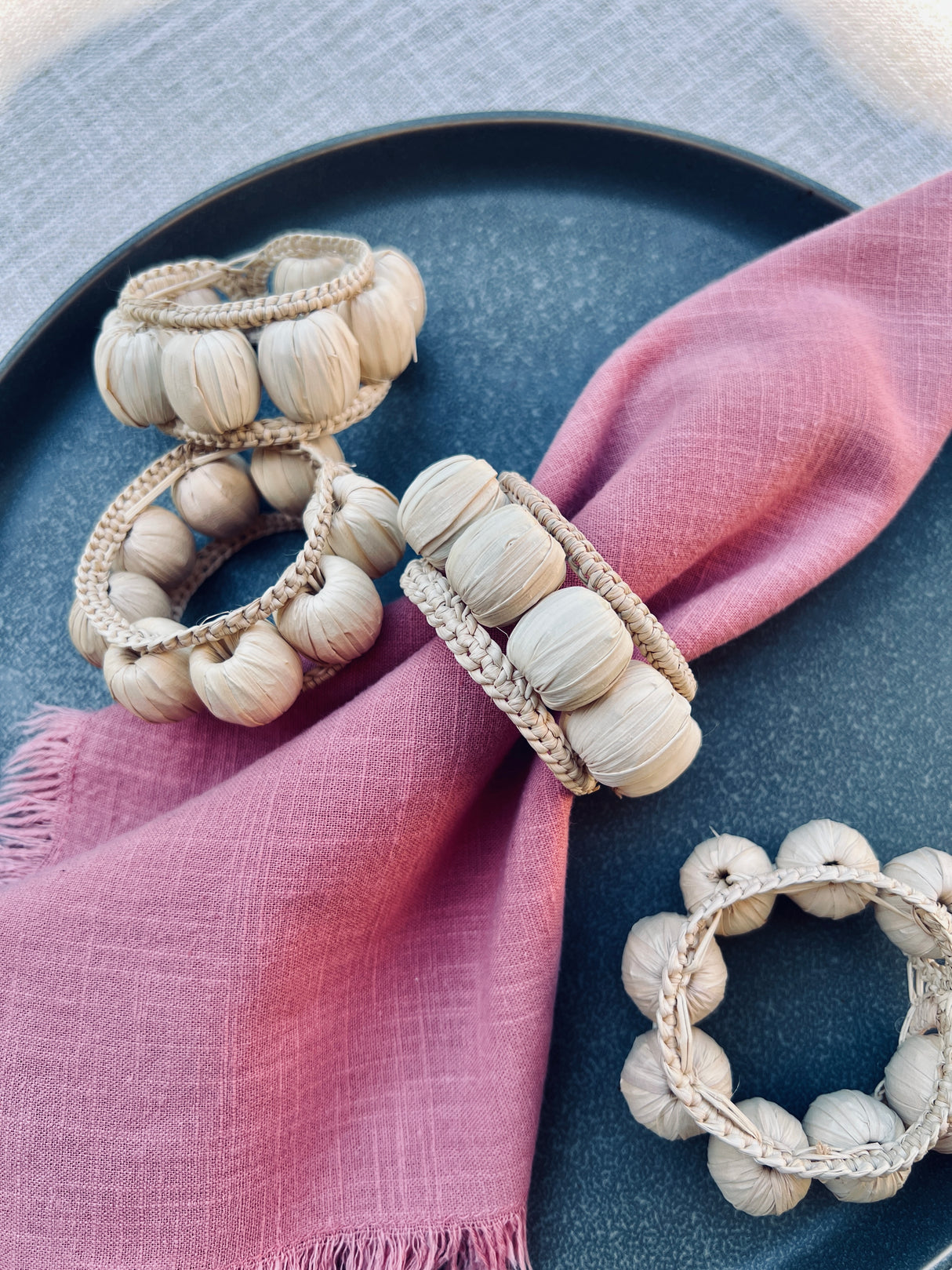 Beaded napkin rings on a pink cloth with a blue plate