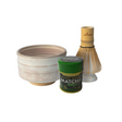Matcha preparation set with a bowl, matcha powder container, and whisk on a white background