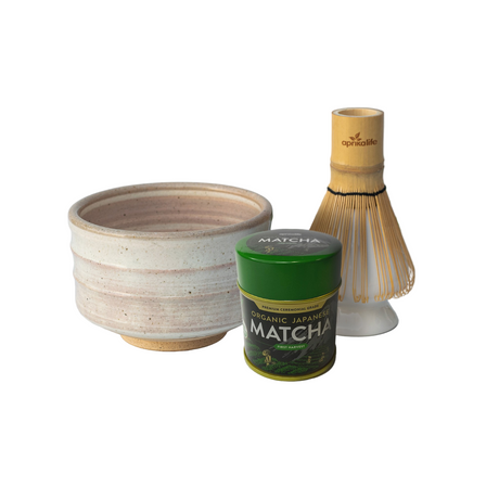 Matcha preparation set with a bowl, matcha powder container, and whisk on a white background