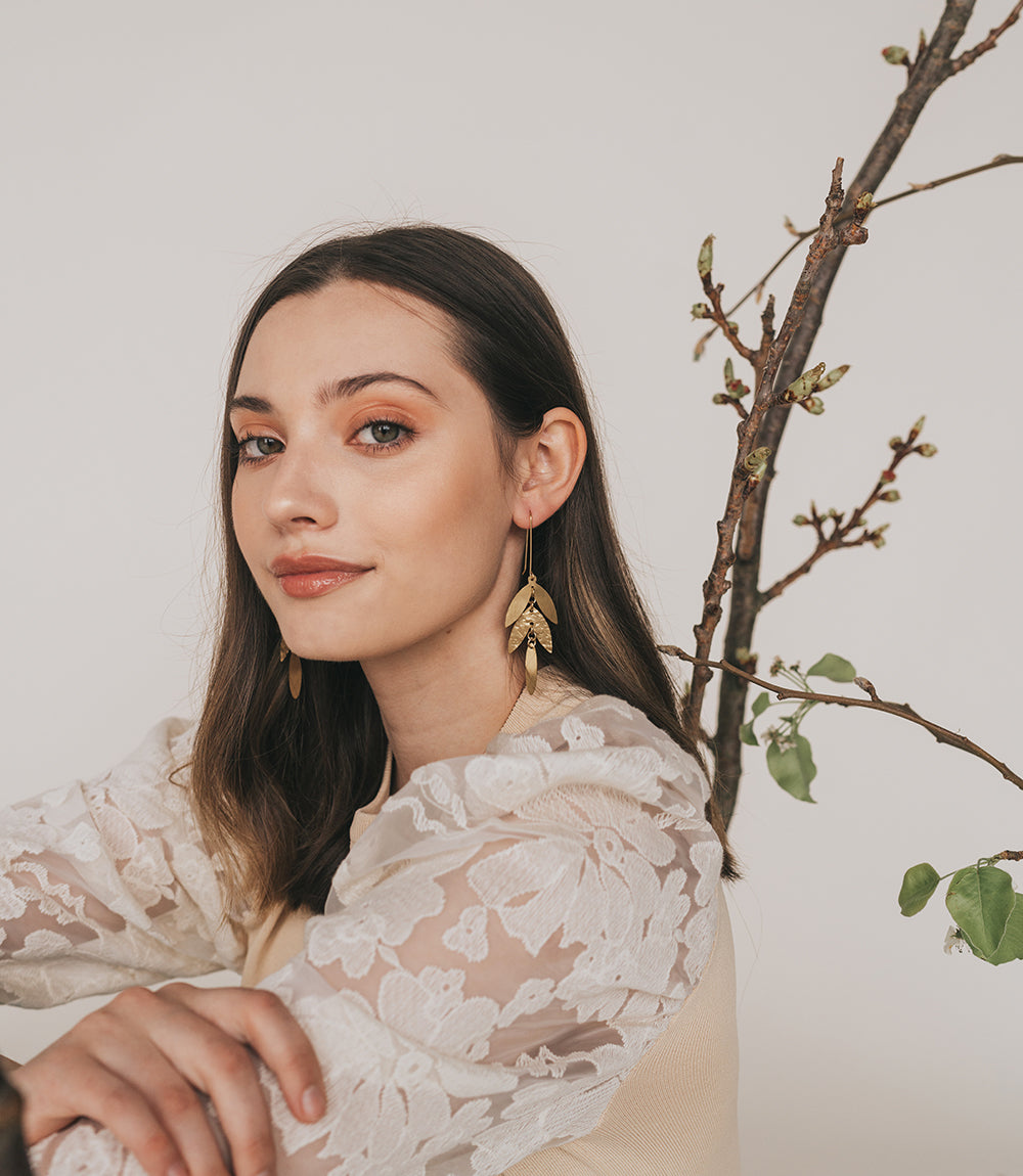 Woman wearing a white lace top with a branch and leaves in the background