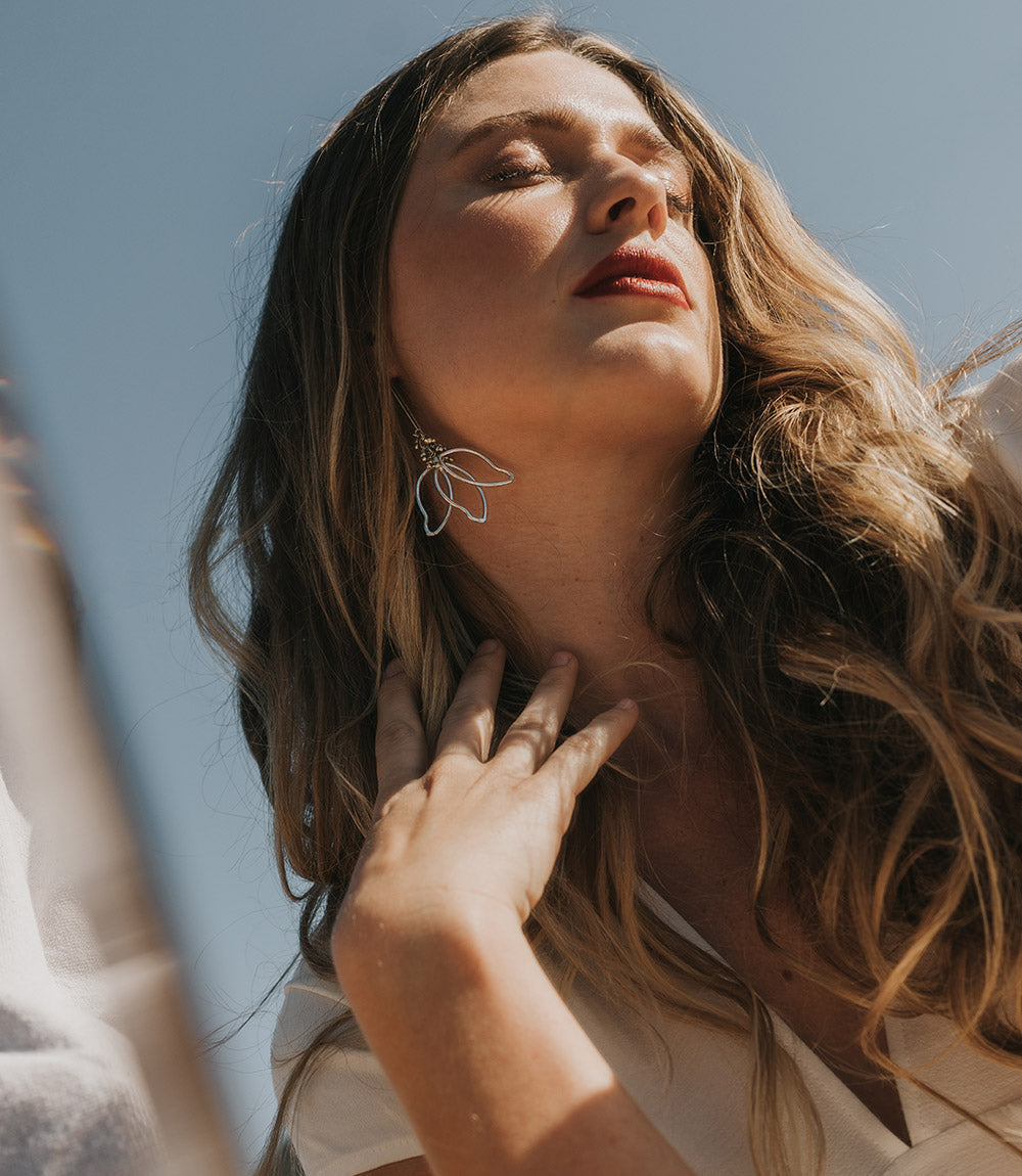 Woman with long hair and a necklace against a clear blue sky