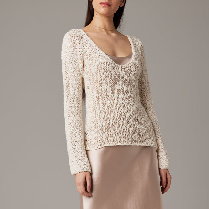 Woman wearing a beige knitted sweater against a gray background