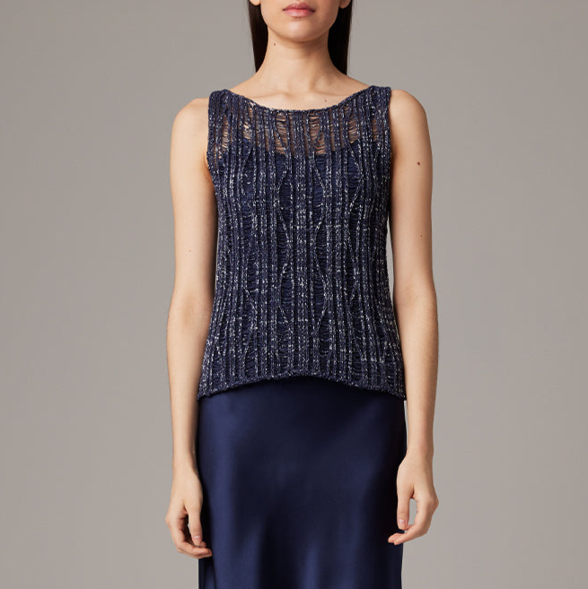 Woman wearing a navy sleeveless top with a textured pattern on a gray background