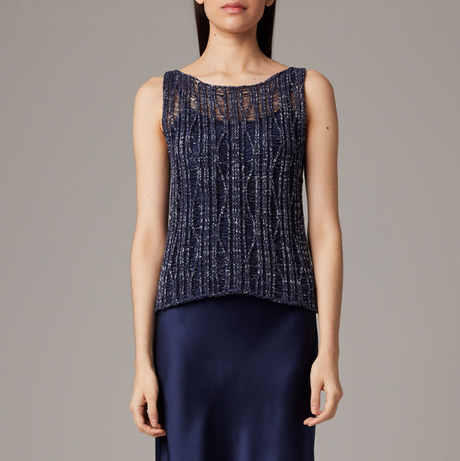 Woman wearing a navy sleeveless top with a textured pattern on a gray background