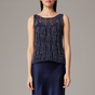 Woman wearing a navy sleeveless top with a textured pattern on a gray background