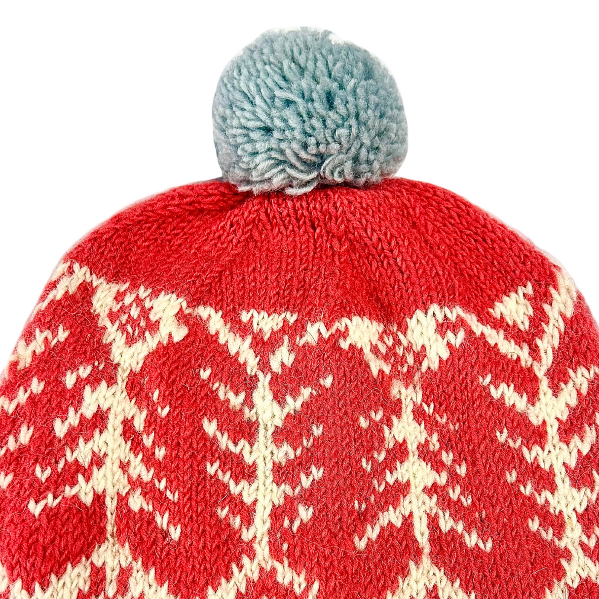 Red knit beanie with white pattern and gray pom-pom on a white background
