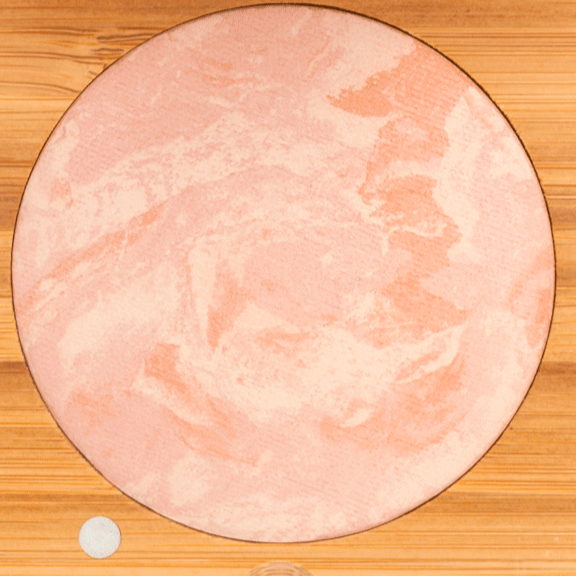 Round pink makeup blush on a wooden surface