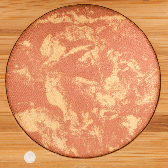 Round blush compact on a wooden surface