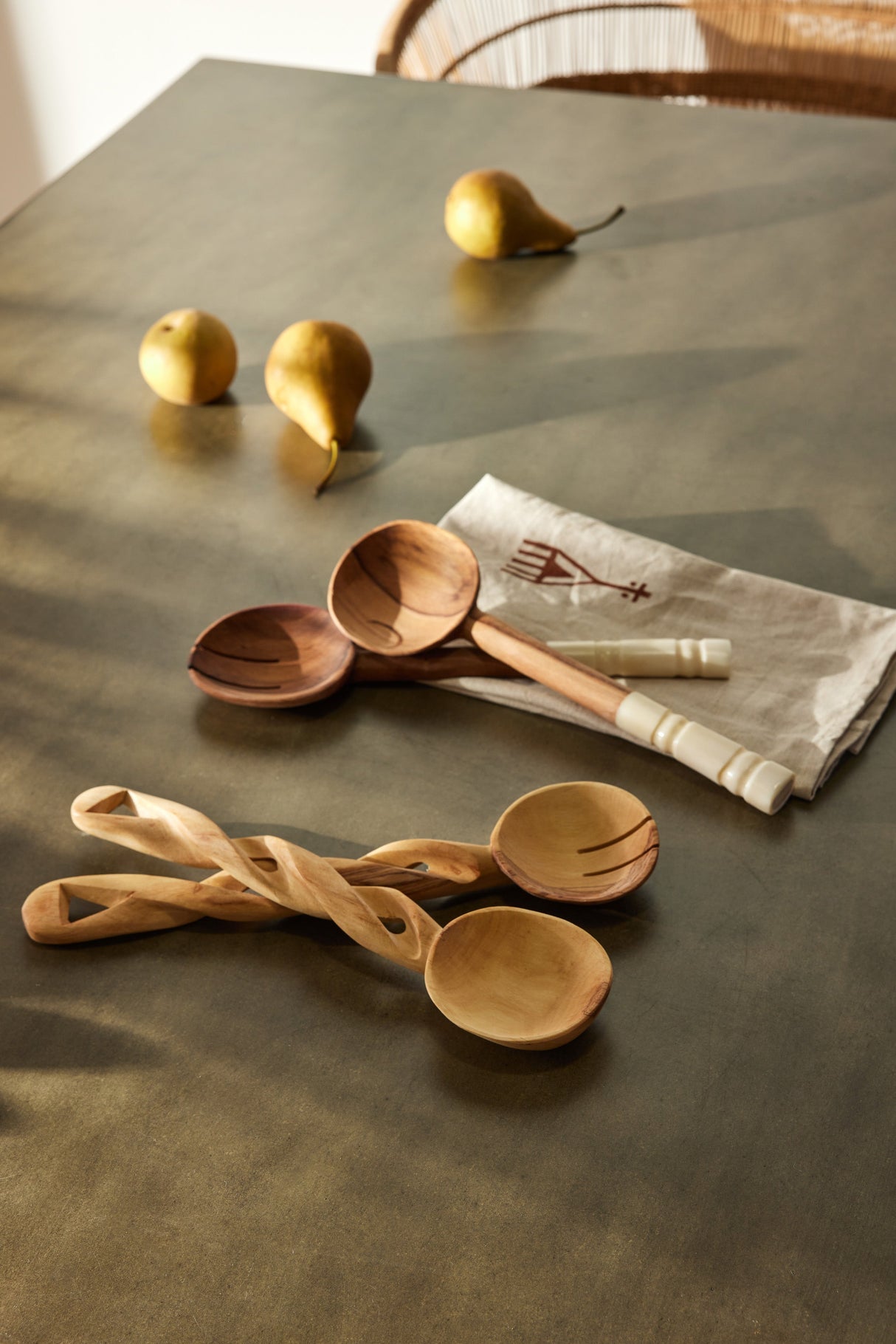 Wooden spoons and pears on a table with a cloth napkin.