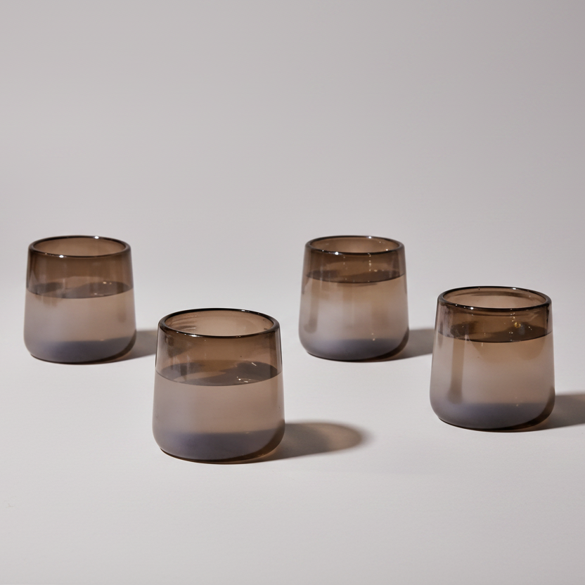 Four smoked glass tumblers on a light gray background
