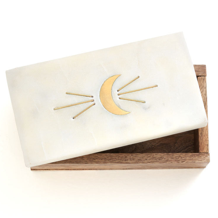 White clutch with gold crescent moon design on a wooden box