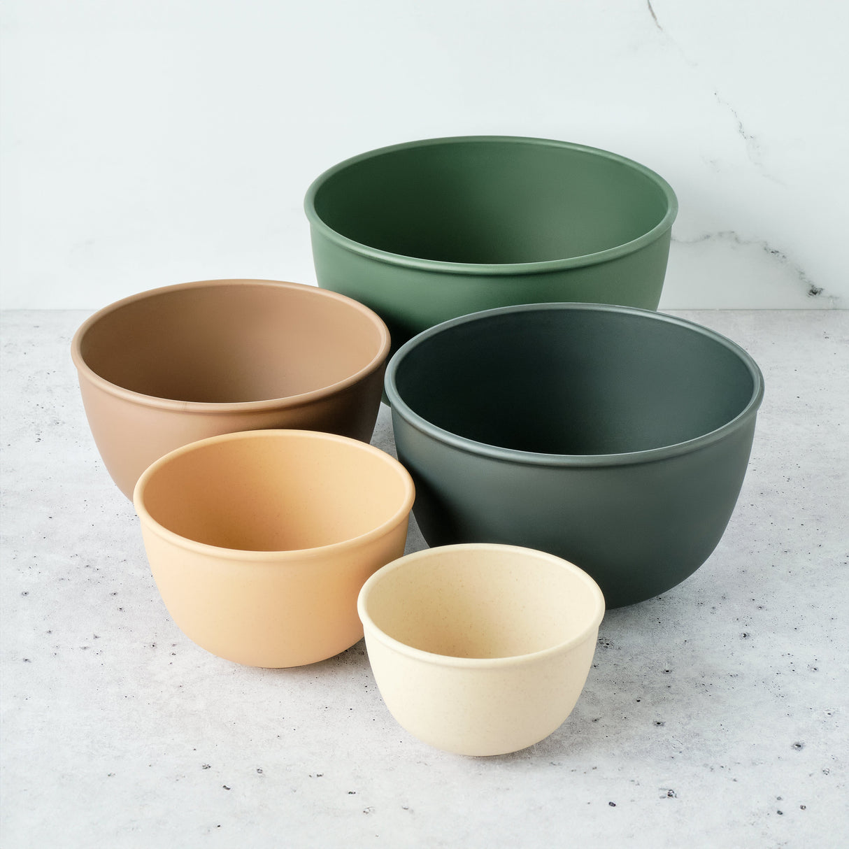 Set of five bowls in different colors on a light gray surface