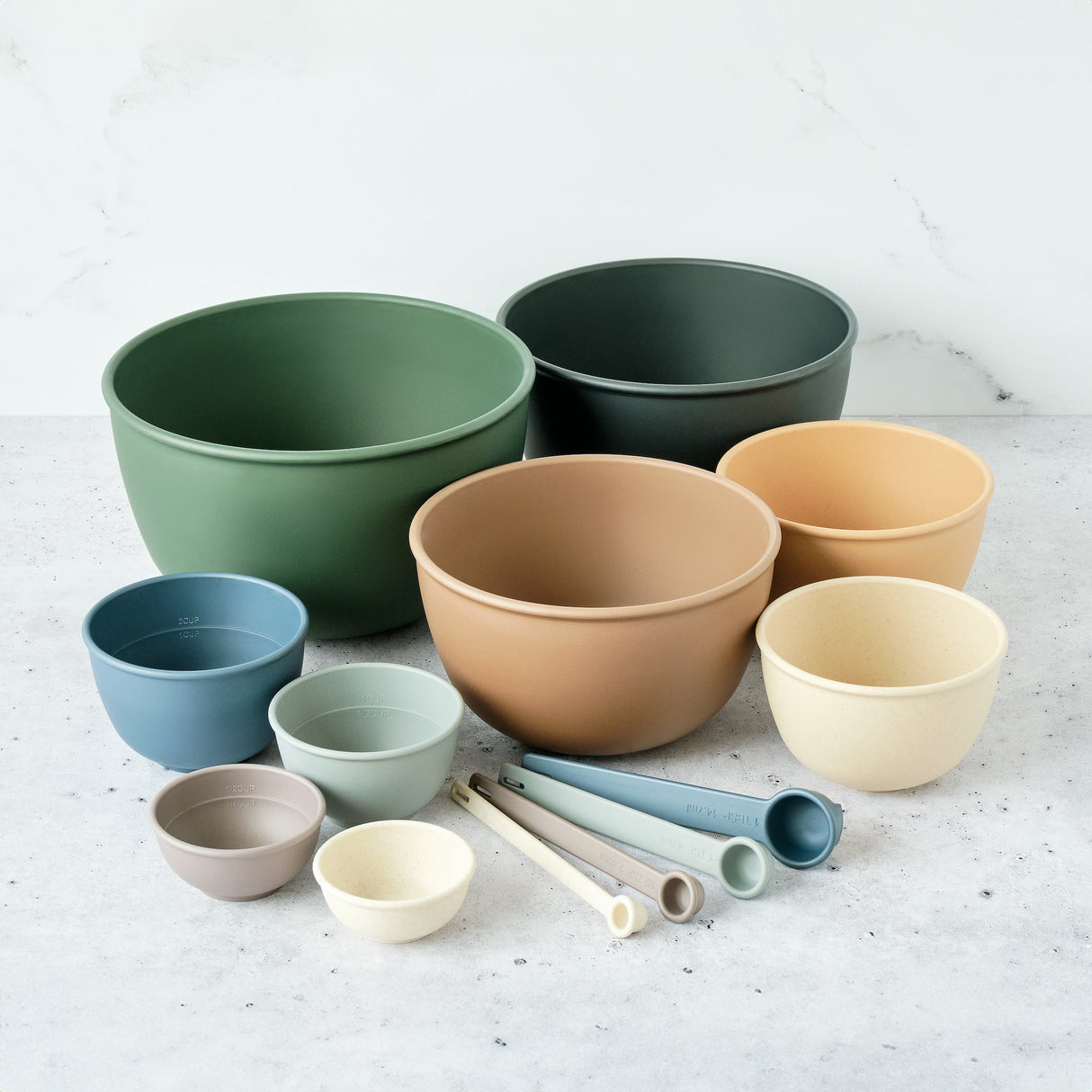 Set of colorful bowls and measuring cups on a light surface