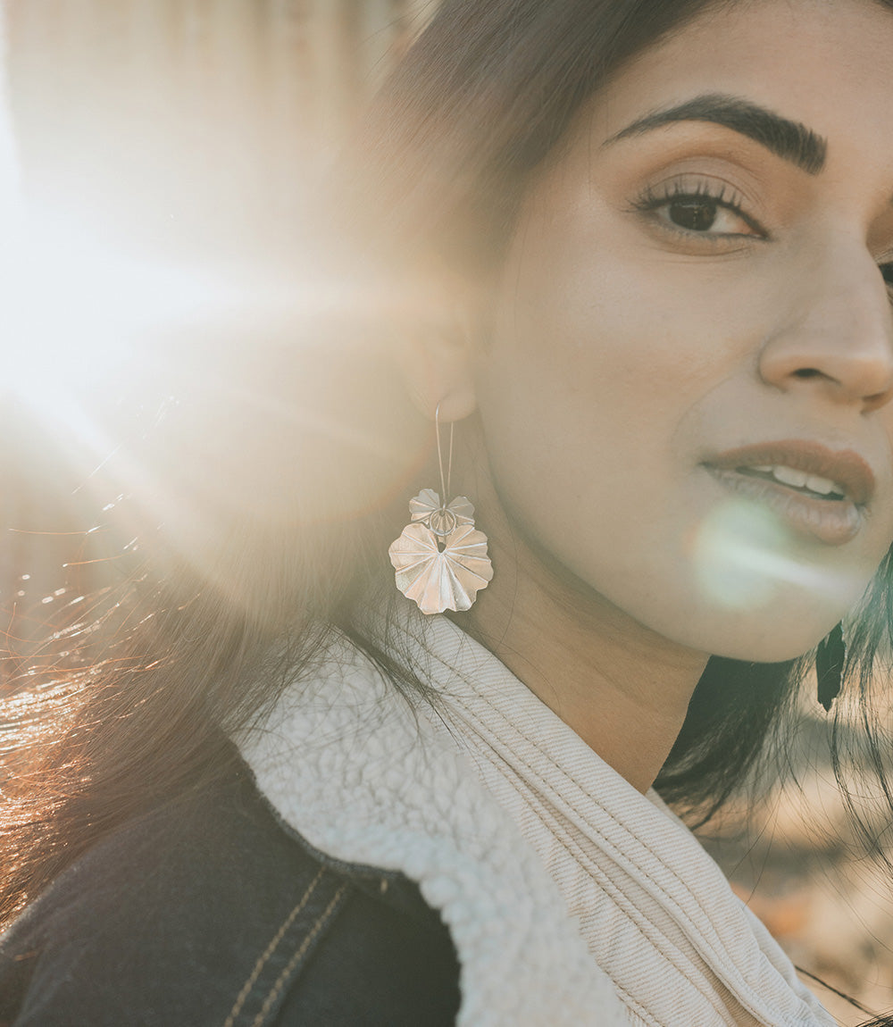Close-up of a woman wearing floral earrings with a blurred background
