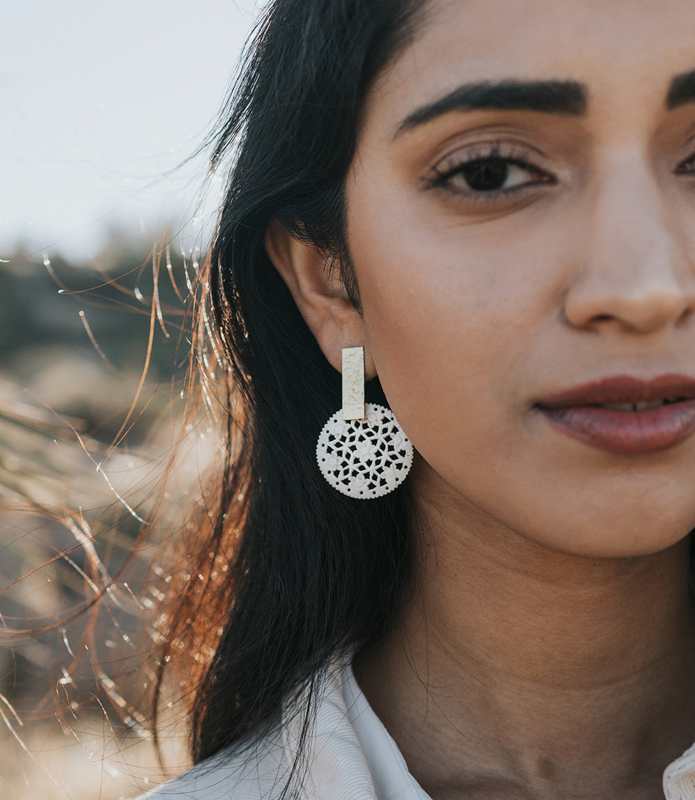 Close-up of a woman wearing a silver earring with a textured design.