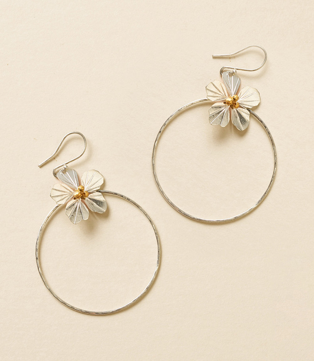 Gold hoop earrings with floral designs on a beige background