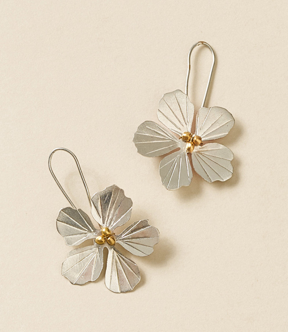 Floral silver earrings with gold centers on a beige background