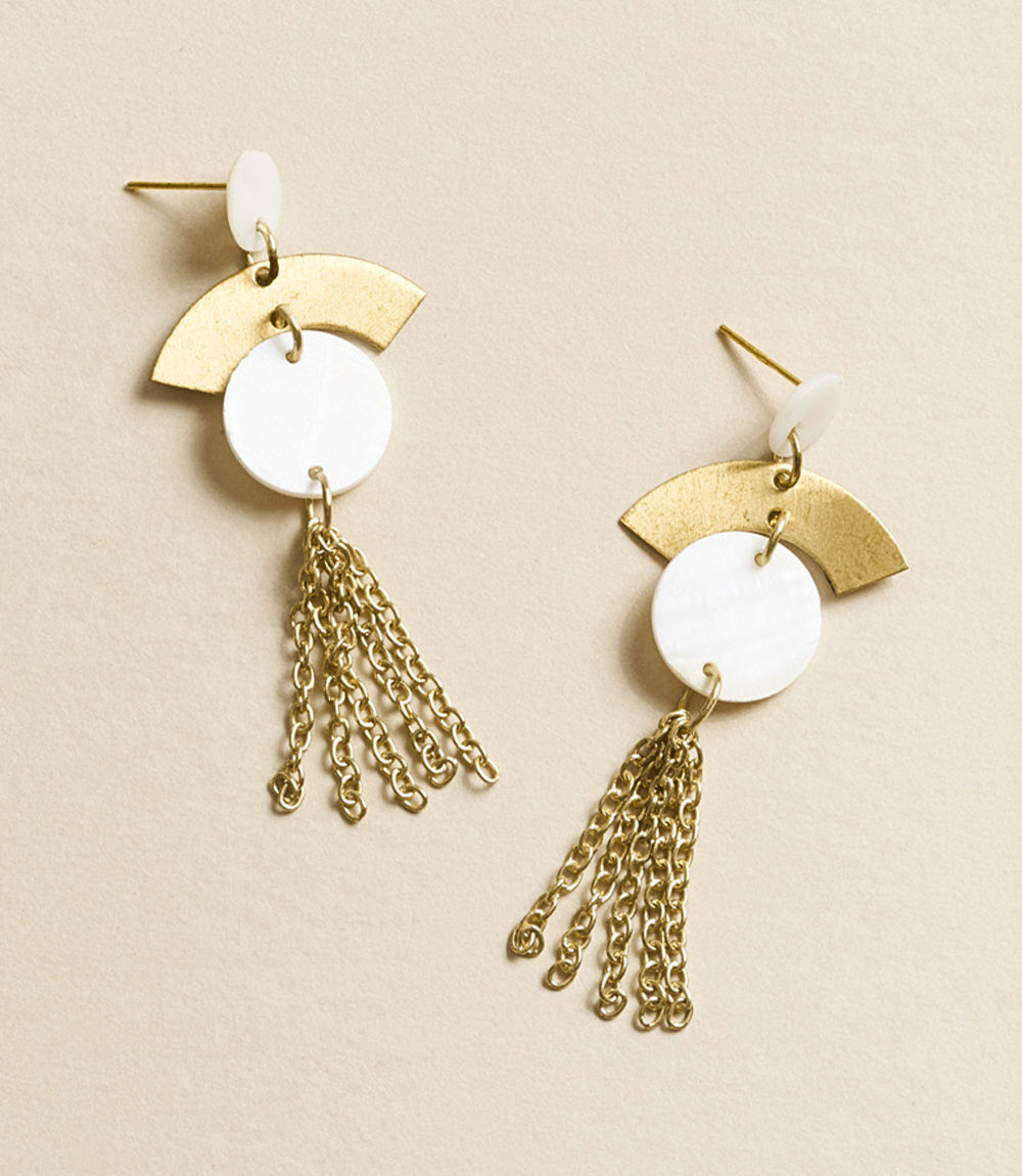 Gold and white earrings with chain tassels on a beige background