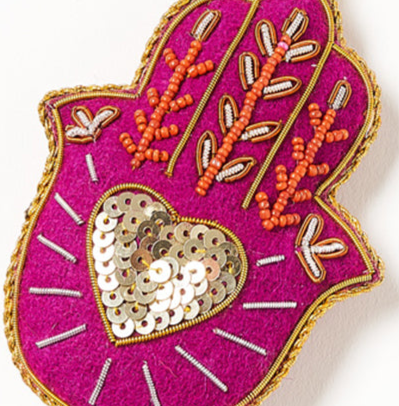 Decorative pink heart-shaped object with gold and orange embellishments on a white background