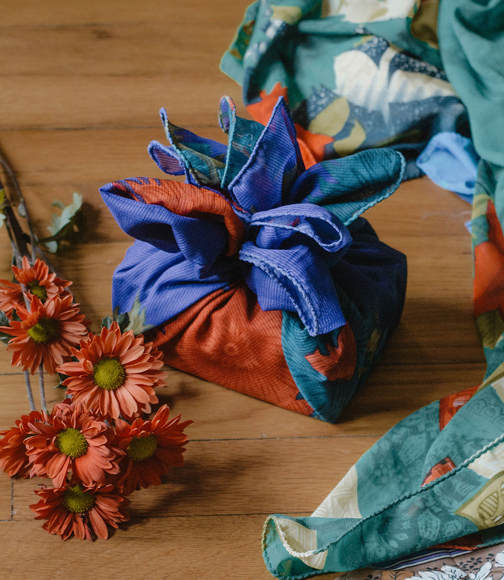 Colorful fabric flower arrangement on a wooden surface with orange flowers.