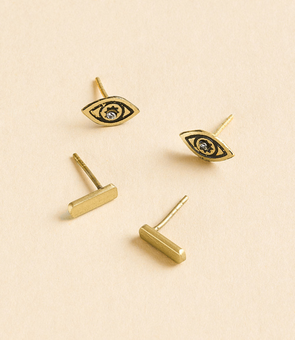 Gold earrings with eye design on a beige background
