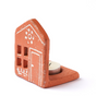Terracotta house-shaped candle holder with a white door on a white background