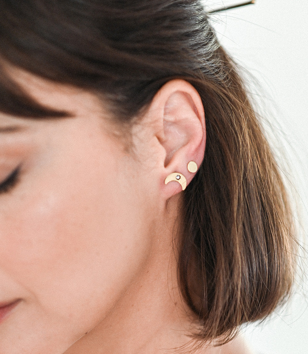 Close-up of a person wearing gold earrings with a neutral background