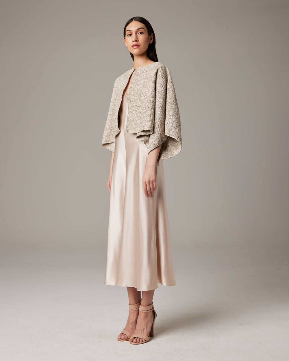 Woman wearing a beige jacket and skirt set on a plain background