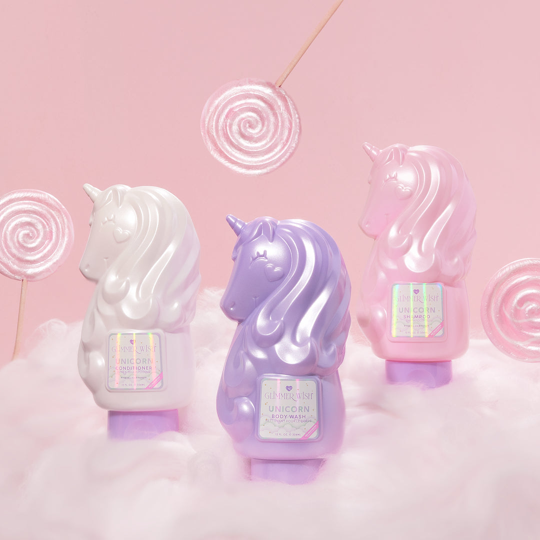 Three unicorn-shaped bath bombs on a pink background with candy swirls.