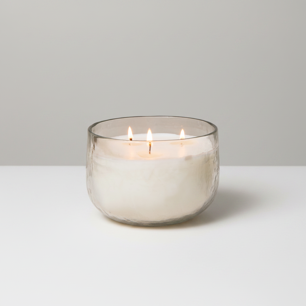 Glass candle holder with a lit candle on a white background