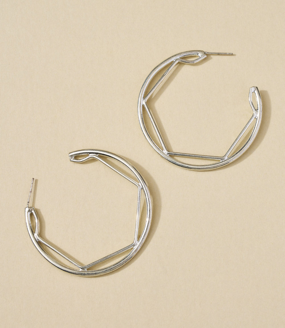 Pair of silver hoop earrings on a beige background