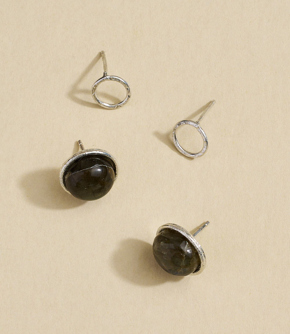 Pair of silver earrings with dark gemstones on a beige background