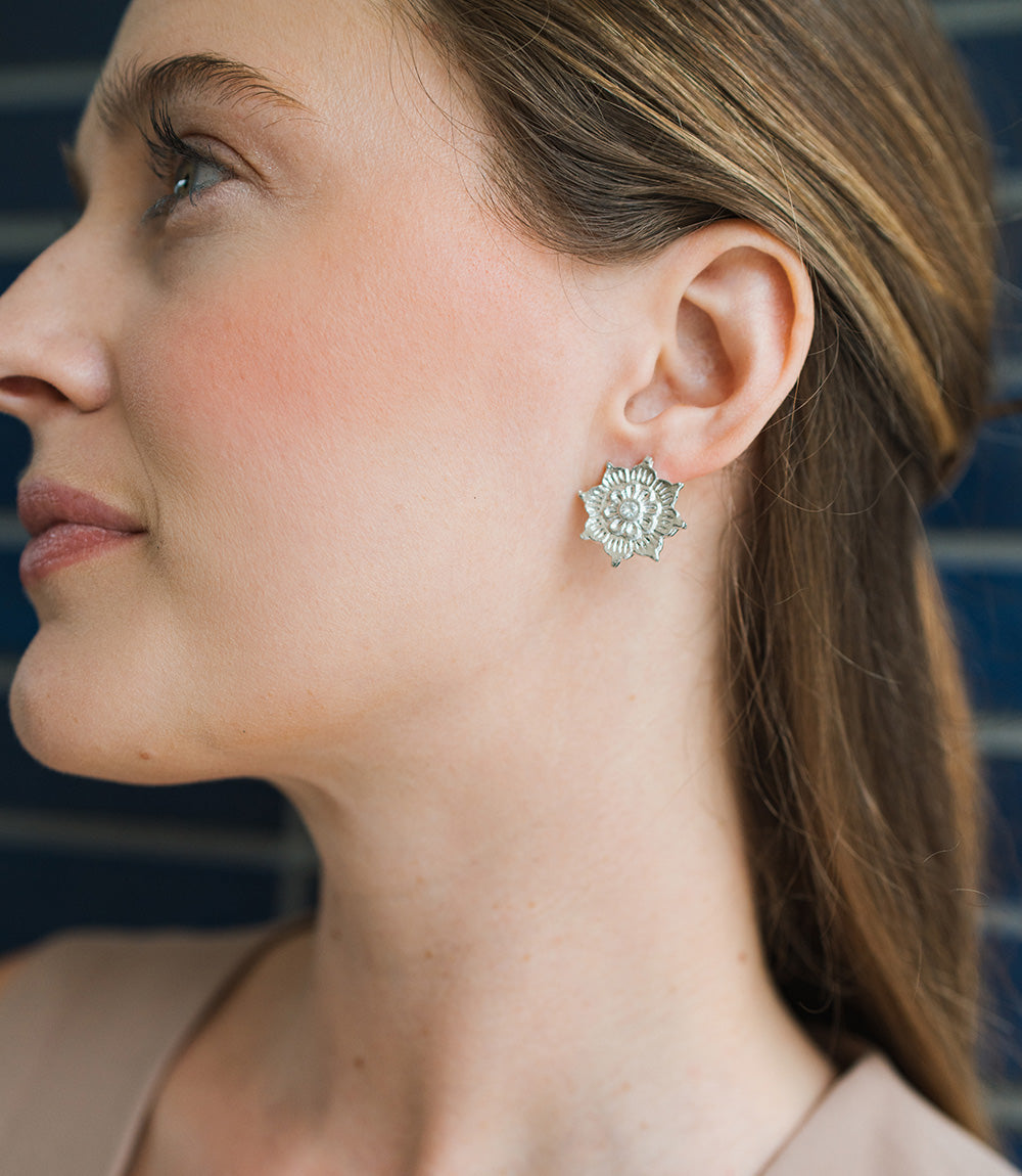 Close-up of a woman wearing a silver floral earring against a blurred background