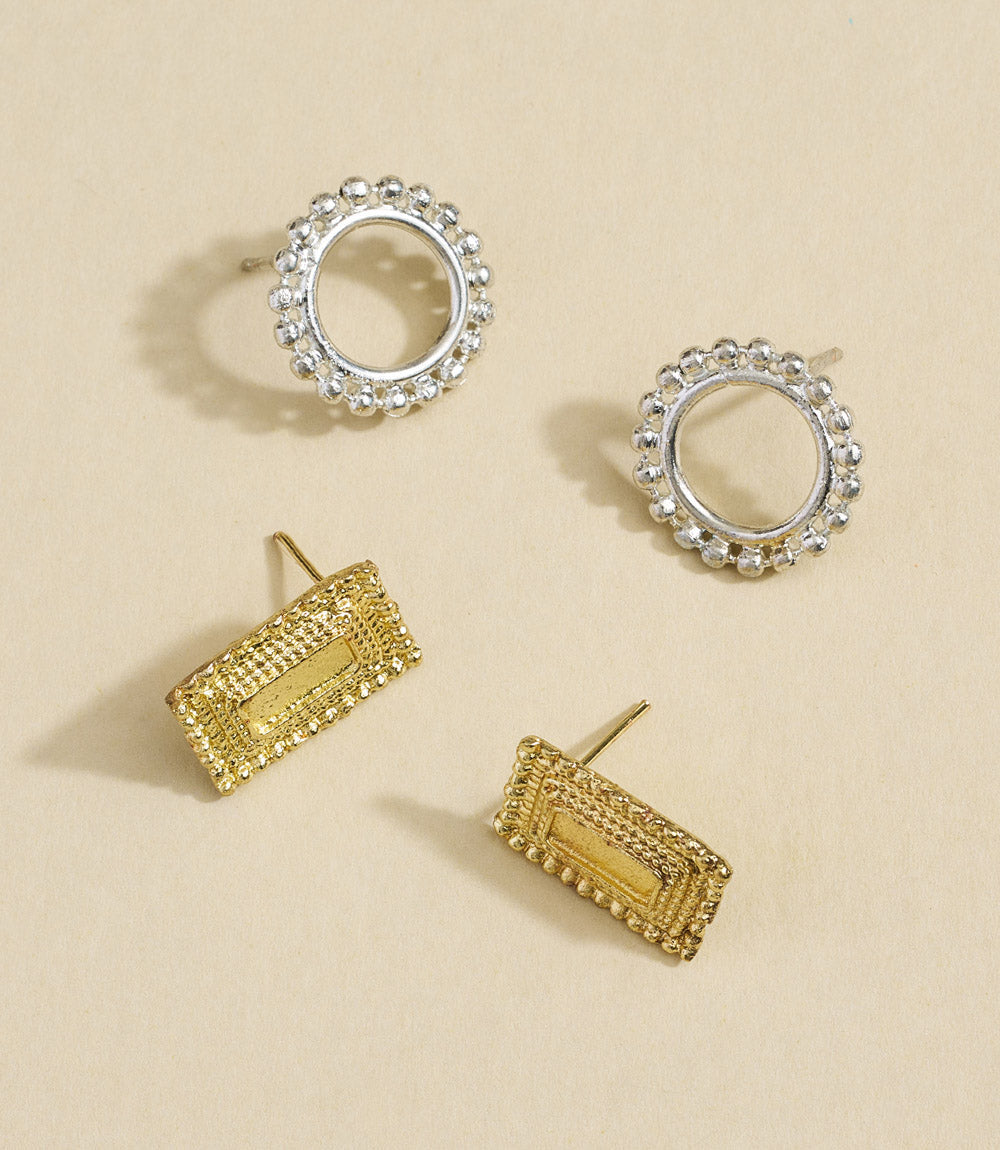 Set of gold and silver hoop earrings on a beige background