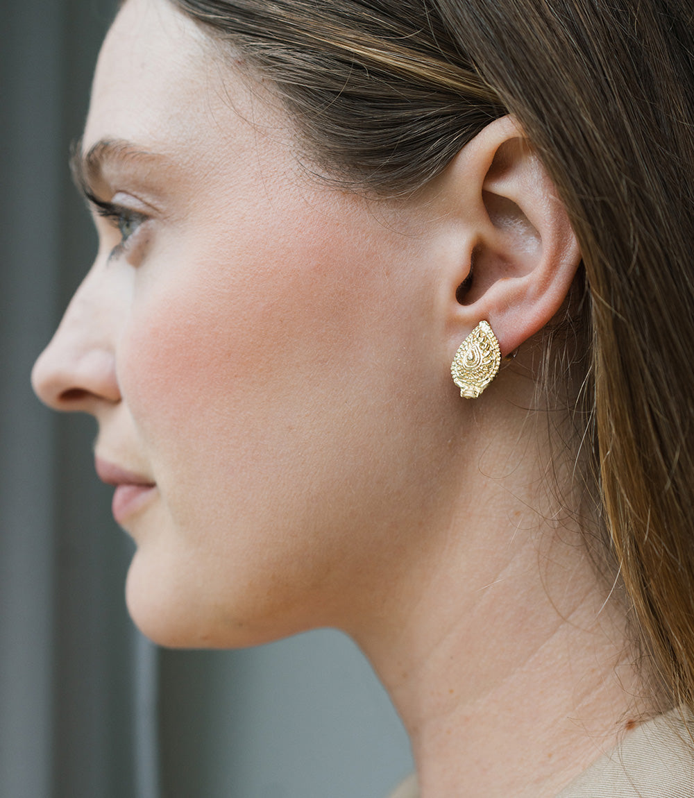 Close-up of a woman wearing gold earrings with a blurred background