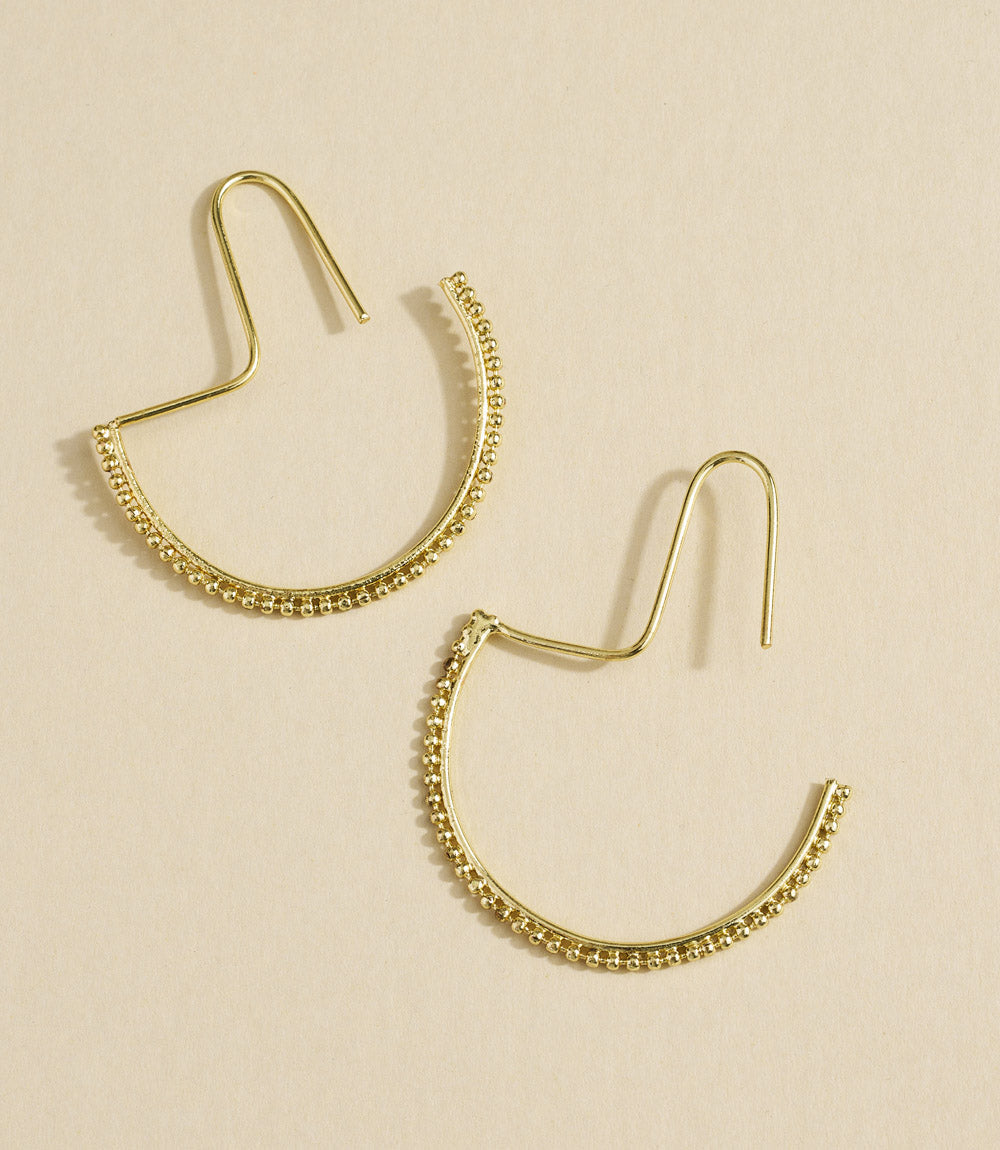 Gold hoop earrings on a beige background