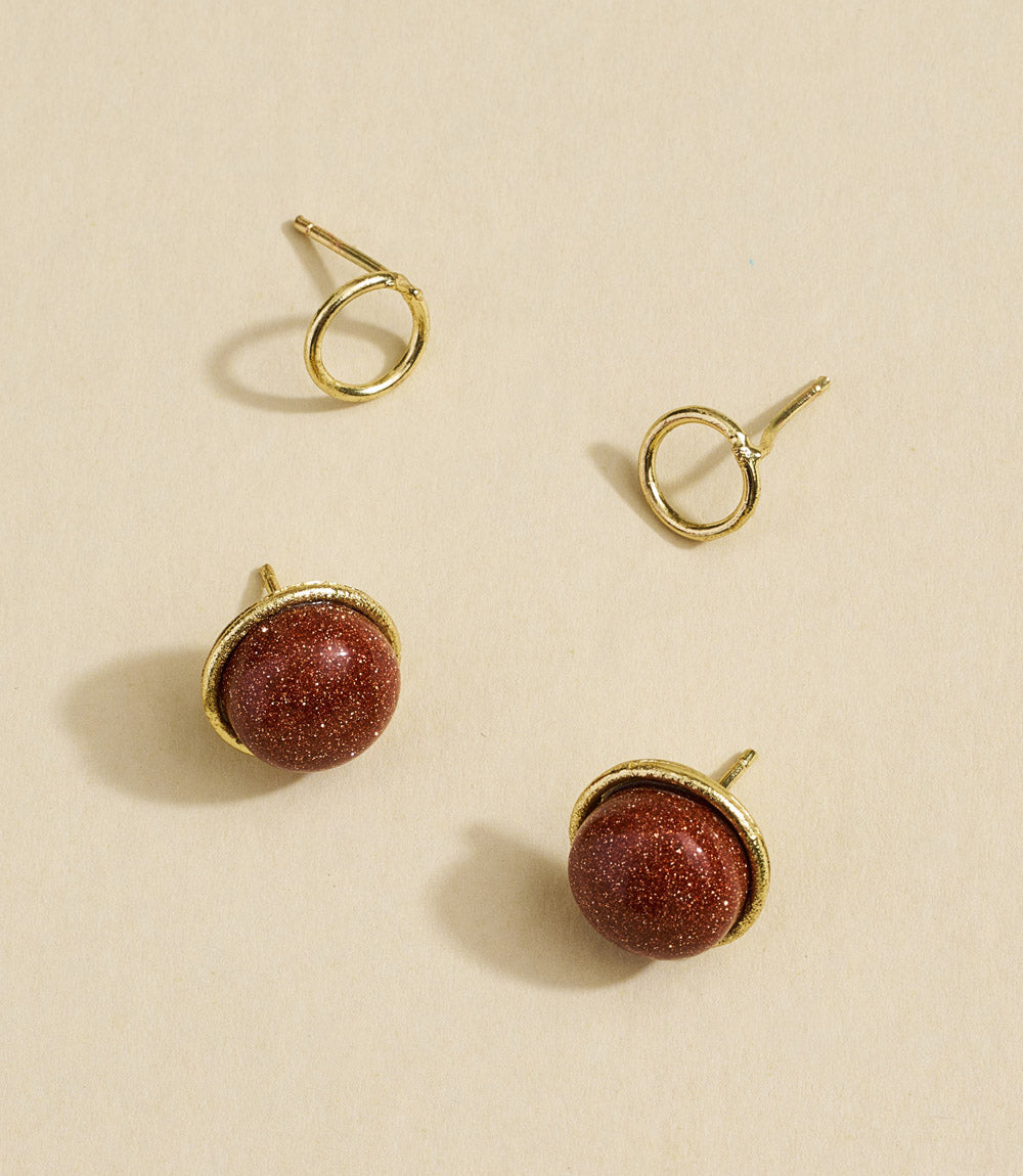 Gold and red stone earrings on a beige background