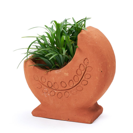 Terracotta planter shaped like a crescent moon with green grass on a white background