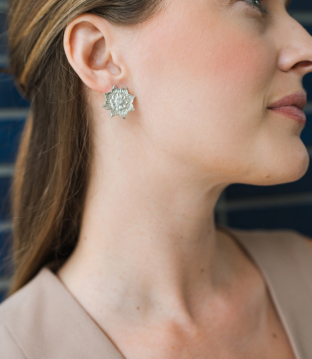 Close-up of a woman wearing a silver floral earring against a blurred background