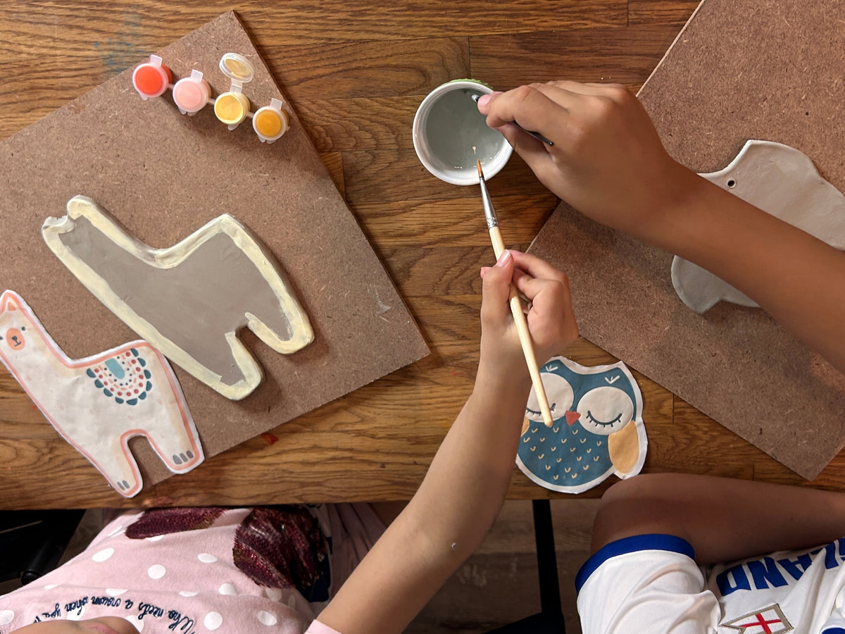 Child painting animal-shaped cookies on a wooden table