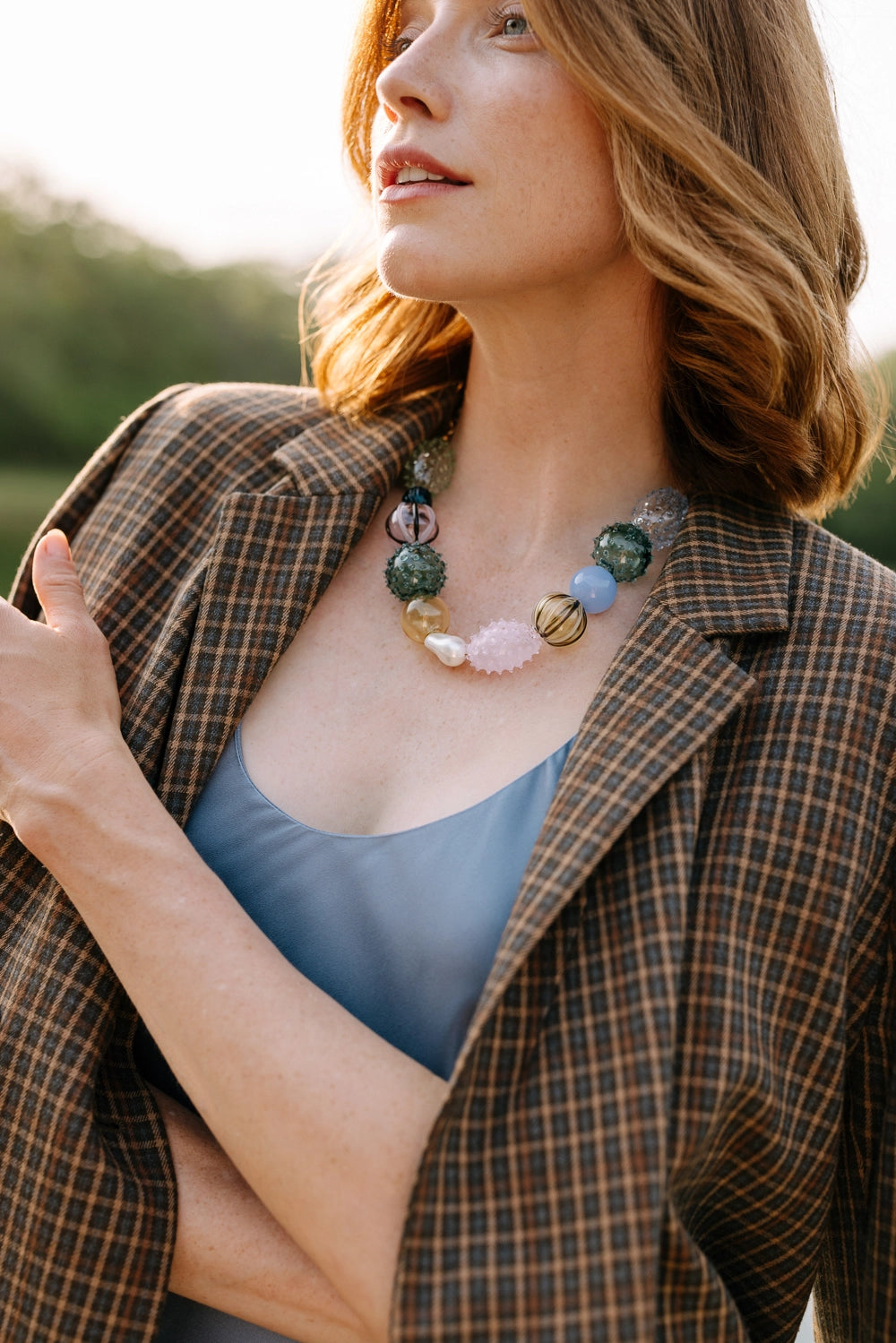 Woman wearing a plaid jacket and colorful necklace outdoors