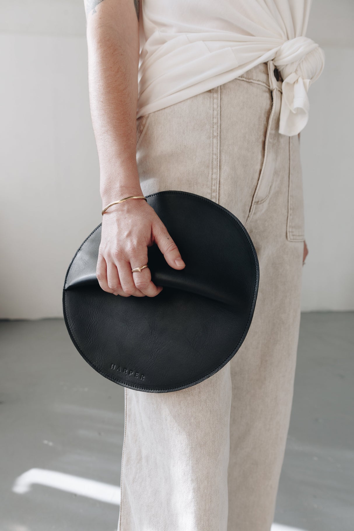 Person holding a black clutch with a neutral background
