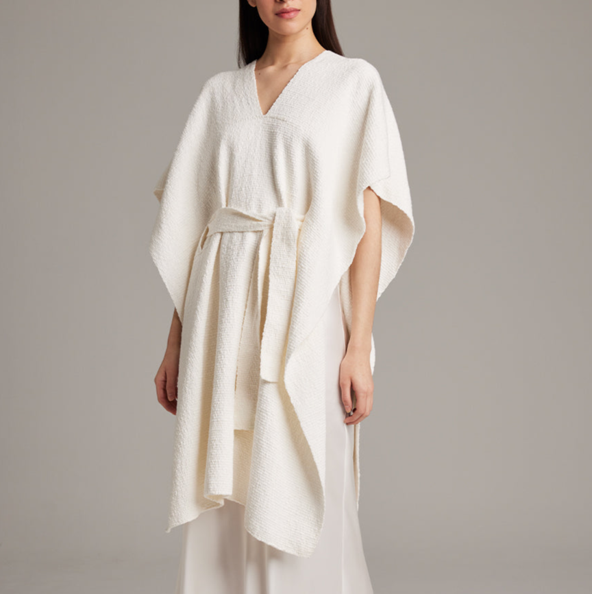 Woman wearing a white dress with a belt against a gray background