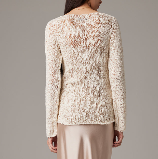 Beige knitted sweater worn by a person on a plain background
