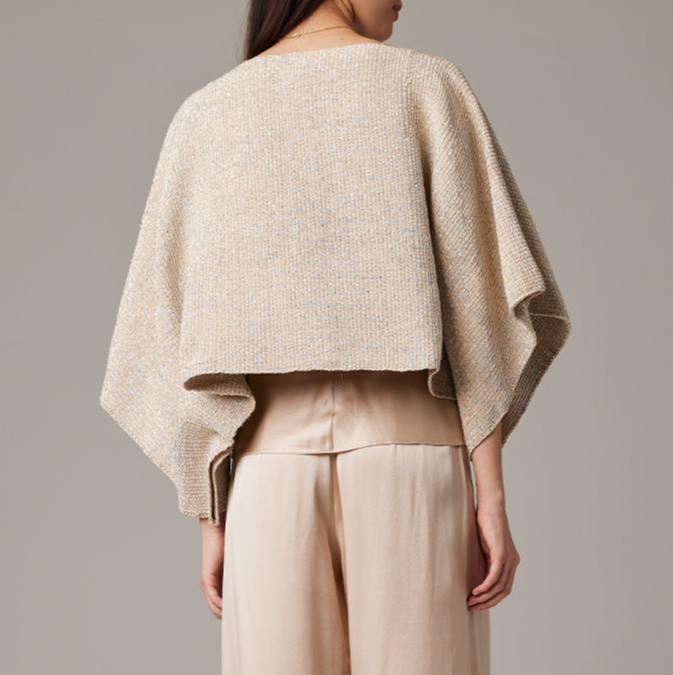Person wearing a beige poncho over a plain background