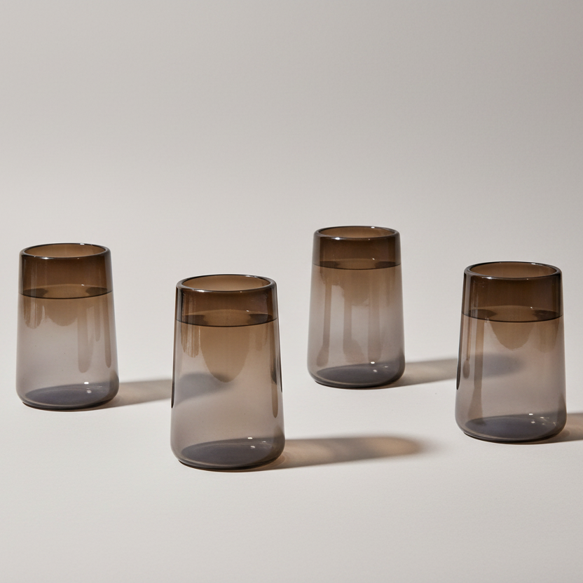 Four smoked glass tumblers on a light gray background